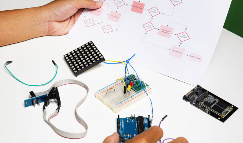 back view hands open flowchart sitting desk using onboard programming debug improve binary algorithm code workstation focusing devices blurring people Saravati