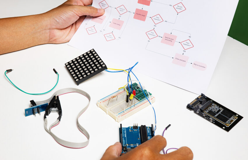 back view hands open flowchart sitting desk using onboard programming debug improve binary algorithm code workstation focusing devices blurring people Saravati