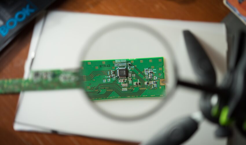 engineer looking circuit board through magnifying glass Saravati